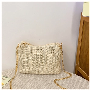 Detail of herringbone weave texture and gold chain strap on beige straw crossbody bag