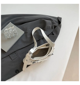 Detail of white biker-style shoulder bag with silver eyelets on a grey blazer