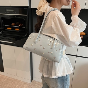 Light blue high-gloss Boston bag with decorative pearls and star rivets in kitchen setting