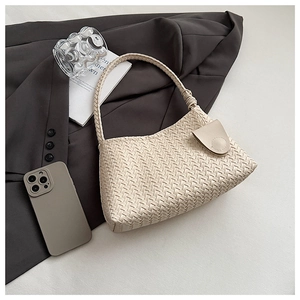Detail of oat-colored woven leather shoulder bag showing intricate texture and knot detail