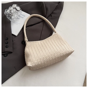 Detailed close-up of beige woven leather texture on a minimalist shoulder handbag