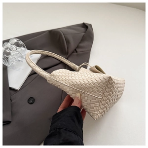 Close-up of beige woven leather tote bag texture on grey suit background