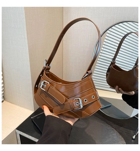 Detail of caramel brown moon bag featuring glossy leather texture and silver metal buckles
