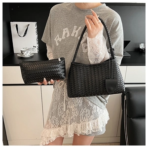 Detail of black woven crescent bag and matching clutch with intricate intrecciato texture