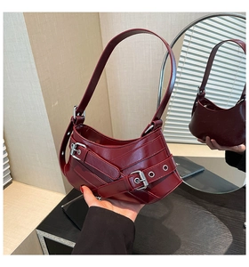 Detailed close-up of burgundy patent leather crescent bag with metallic buckle hardware