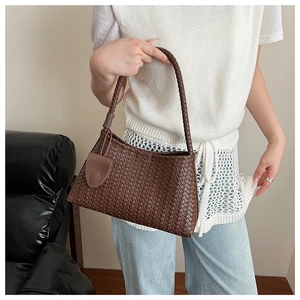 Detail of the woven texture and leather buckle on a dark brown intrecciato handbag
