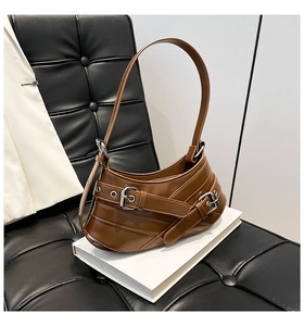 Detail of brown Y2K faux leather shoulder bag featuring decorative metal pin buckles