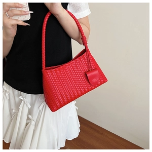 Detailed view of red woven leather underarm bag with minimalist trapezoid structure