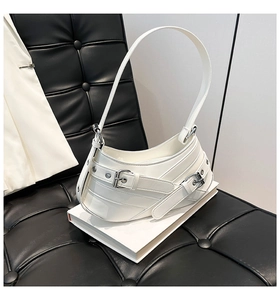 Detail of white glossy leather handbag featuring decorative metal buckles in Y2K style