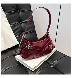 Close-up of deep red leather shoulder bag with silver metallic buckles and biker style