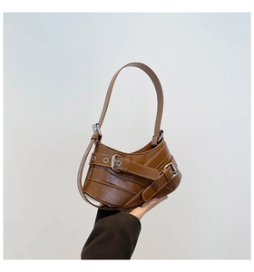 Detail of vintage brown shoulder bag featuring metallic buckle straps and Y2K aesthetic