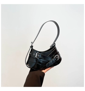Close-up of black glossy leather shoulder bag with silver buckles and Y2K punk style straps
