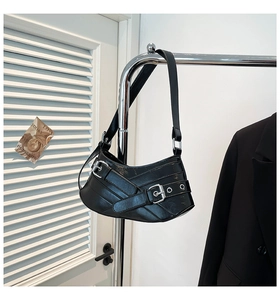 Detail of black glossy faux leather shoulder bag with silver buckles and Y2K punk style