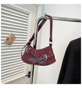 Close-up of wine red glossy leather shoulder bag with vintage silver metal buckles
