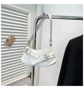 Detail of white glossy leather hobo bag with silver buckles hanging on metal rail