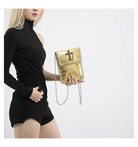 Détail de la texture crocodile dorée et de la croix noire sur le sac à bandoulière