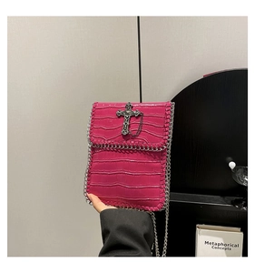 Vue détaillée du sac rose rouge à motif crocodile avec croix en métal et chaîne punk