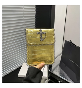 Détail du sac doré texture crocodile avec croix vintage argentée et bandoulière chaîne