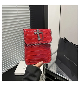 Détail du sac de téléphone rouge effet croco avec croix gothique et bordure de chaîne