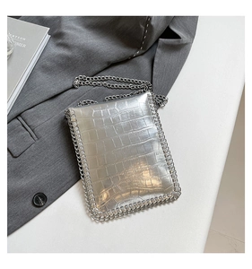 Détail du sac bandoulière argenté métallisé à motif crocodile sur un blazer gris