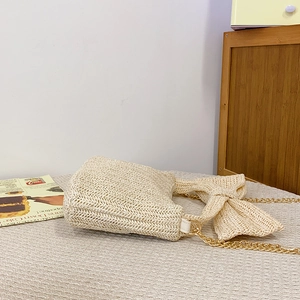 Elegant beige straw crossbody bag with large bow decoration and gold chain strap