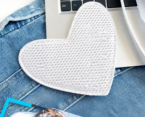 Detailed view of a white heart-shaped mesh board insert for pins on denim fabric