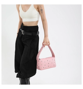Detailed view of pink baguette bag with silver studs worn by a model in casual outfit