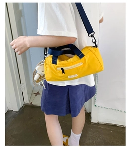 Dettaglio della borsa da viaggio in nylon giallo con ciondolo a forma di orso bianco