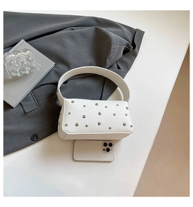 Detailed macro view of white rivet handbag with leather texture next to a smartphone
