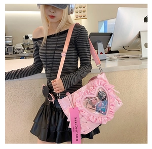 Detail of pink pleated ita bag with heart-shaped transparent window and ruffle trim