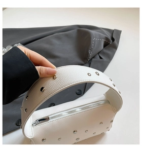 Macro detail of white lychee leather handbag handle with silver metallic rivets