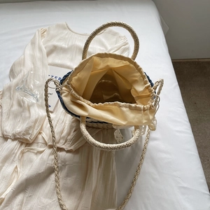 Woven straw bucket bag with blue stripes and lace details in a 45-degree lifestyle view