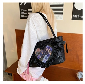 Detail of black ruffle tote bag with heart-shaped transparent window and ribbon bow