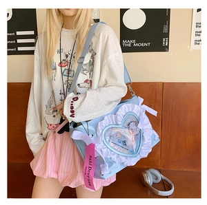 Detail of light blue ita bag with heart-shaped transparent window and lace ruffle