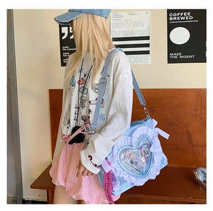 Detailed view of light blue ita bag with heart window and ruffled edges on wooden bench