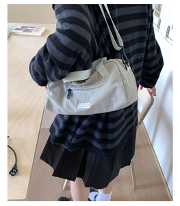 Dettaglio laterale della borsa a tracolla cilindrica beige con cinturino regolabile