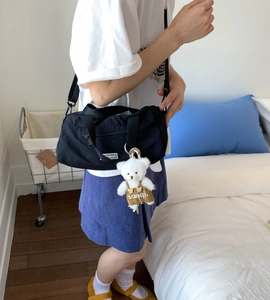 Detail of black nylon Boston bag with cute plush bear charm for daily travel and sport