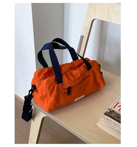 Dettaglio borsa in nylon arancione con manici in tessuto blu e ganci in metallo