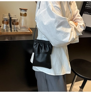 Gros plan d'un sac à téléphone noir avec des volants élégants et un design plissé