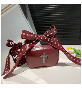 Détail du sac en cuir verni rouge foncé avec pendentif croix gothique et rivets argentés
