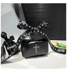 Sac bandoulière gothique en cuir verni noir avec croix argentée et nœud à rivets