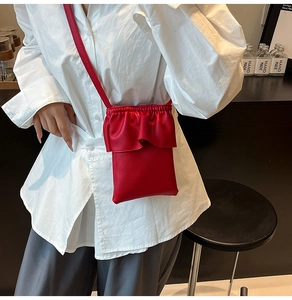 Détail du mini sac à bandoulière en cuir rouge avec bordure à volants et motif litchi