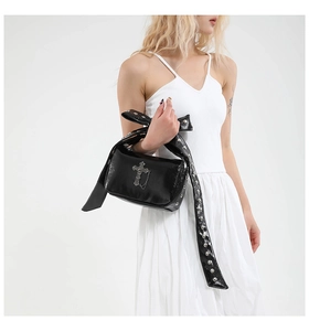 Détail du sac gothique noir brillant avec croix argentée et bandoulière à rivets