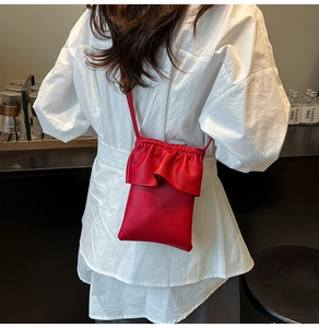 Détail du petit sac à téléphone en cuir rouge avec volants et cordon de serrage