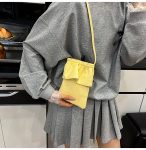 Gros plan d'un mini sac de téléphone jaune en cuir grainé avec détails de volants