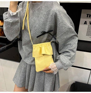 Détail du mini sac bandoulière jaune en cuir grainé avec une bordure à volants