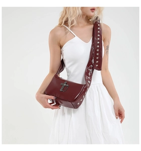 Détail du sac en cuir verni rouge bordeaux avec rivets et pendentif croix