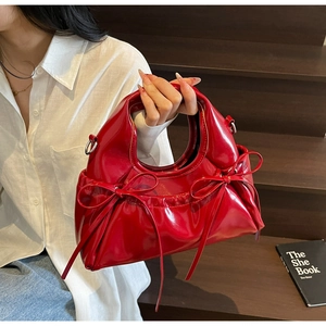 Close-up of bright red patent leather handbag with bow details and mirror shine finish