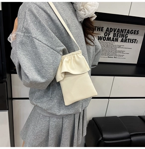 Petit sac de téléphone vertical blanc crème avec bords à volants et texture grainée sur modèle