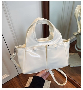 Detail of cream white faux leather tote bag showing front pockets and adjustable strap